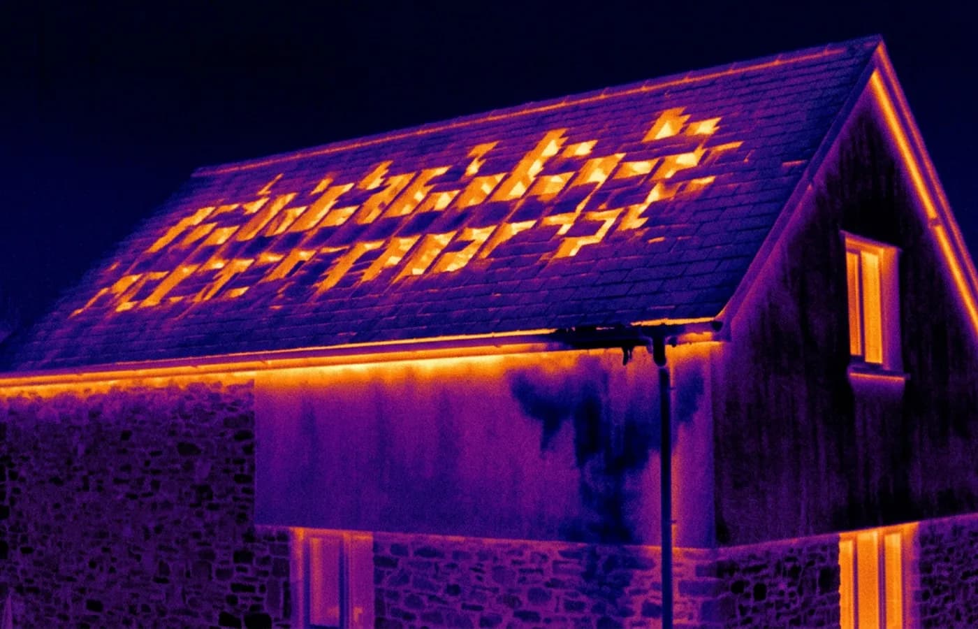 Radiometric thermal image of a house gable and roof slope in the ironbow palette, showing warm patches where loft insulation is missing between joists and a cool damp area below a blocked gutter